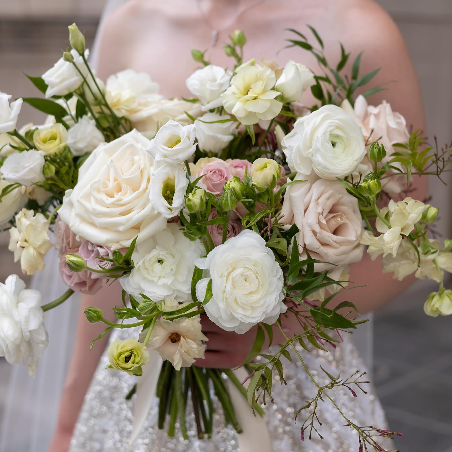 a bride holding a soft, blush-and-ivory Flowers for Dreams bridal bouquet with roses and greenery.