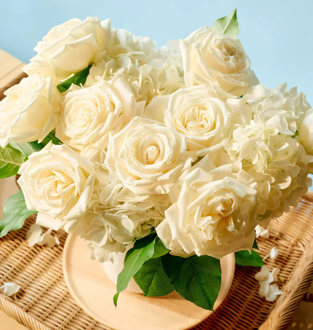 Soft white and cream sympathy bouquet featuring seasonal blooms arranged in a clear glass vase.