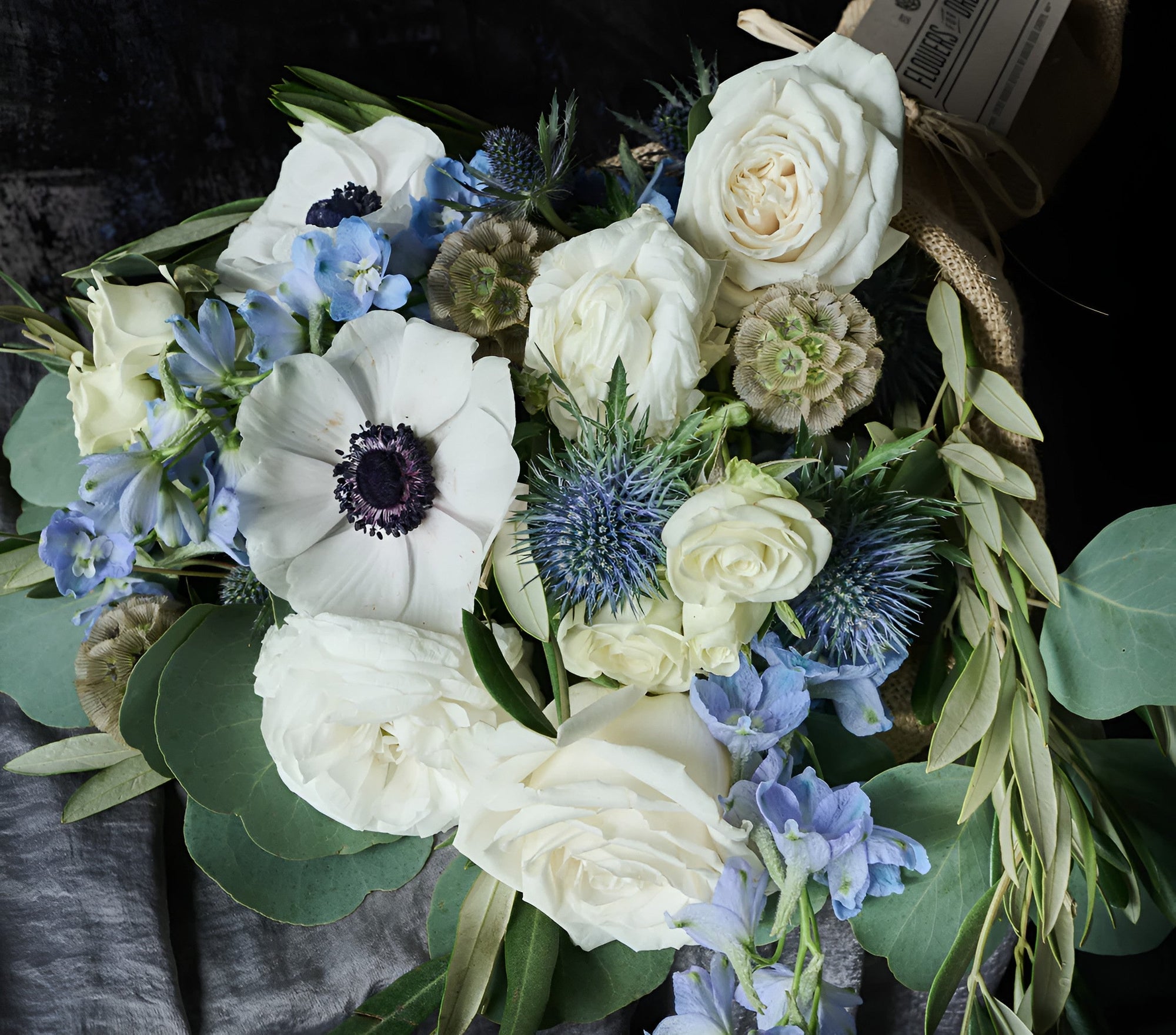 Flower for Dreams winter bouquet with white roses, blue thistles, and anemones in soft, cool tones.