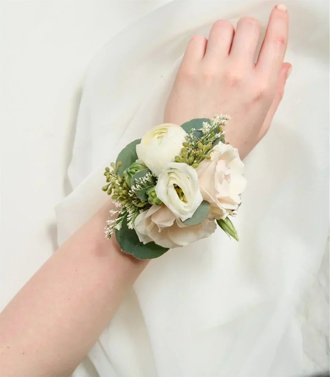 Elegant floral wrist corsage with white roses and greenery on a white background from Flowers for Dreams.
