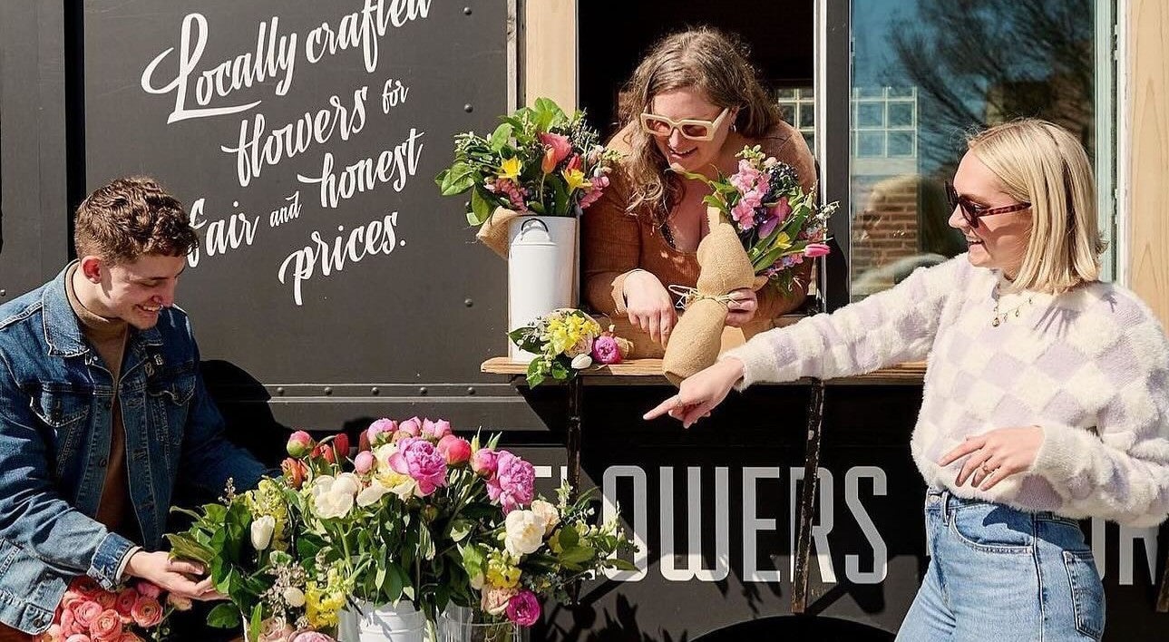 People buying fresh, locally crafted flower bouquets from a boutique flower truck.