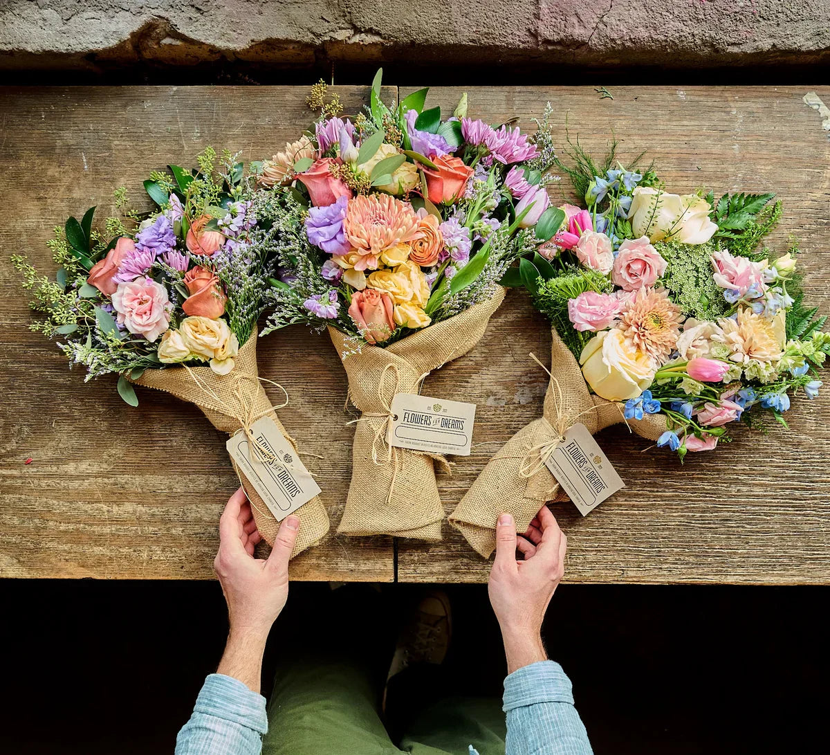 Hands wrapping a rustic bouquet in burlap at Flowers for Dreams