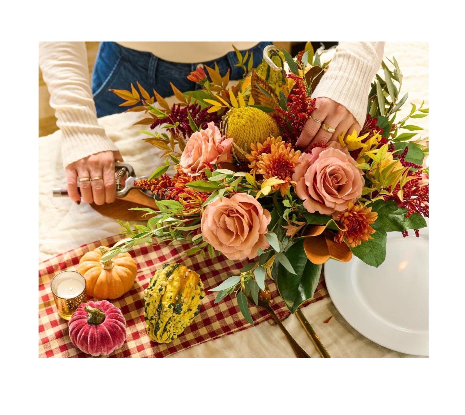 Crafting a lush table centerpiece at Flowers of Dream with peach roses, mums, foliage, gourds, and pumpkins.
