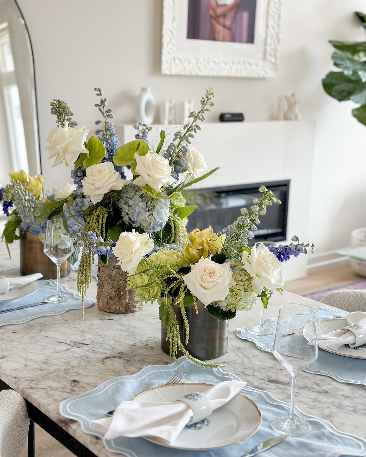 Elegant white and blue floral arrangements by Flowers for Dreams on a marble dining table set. 